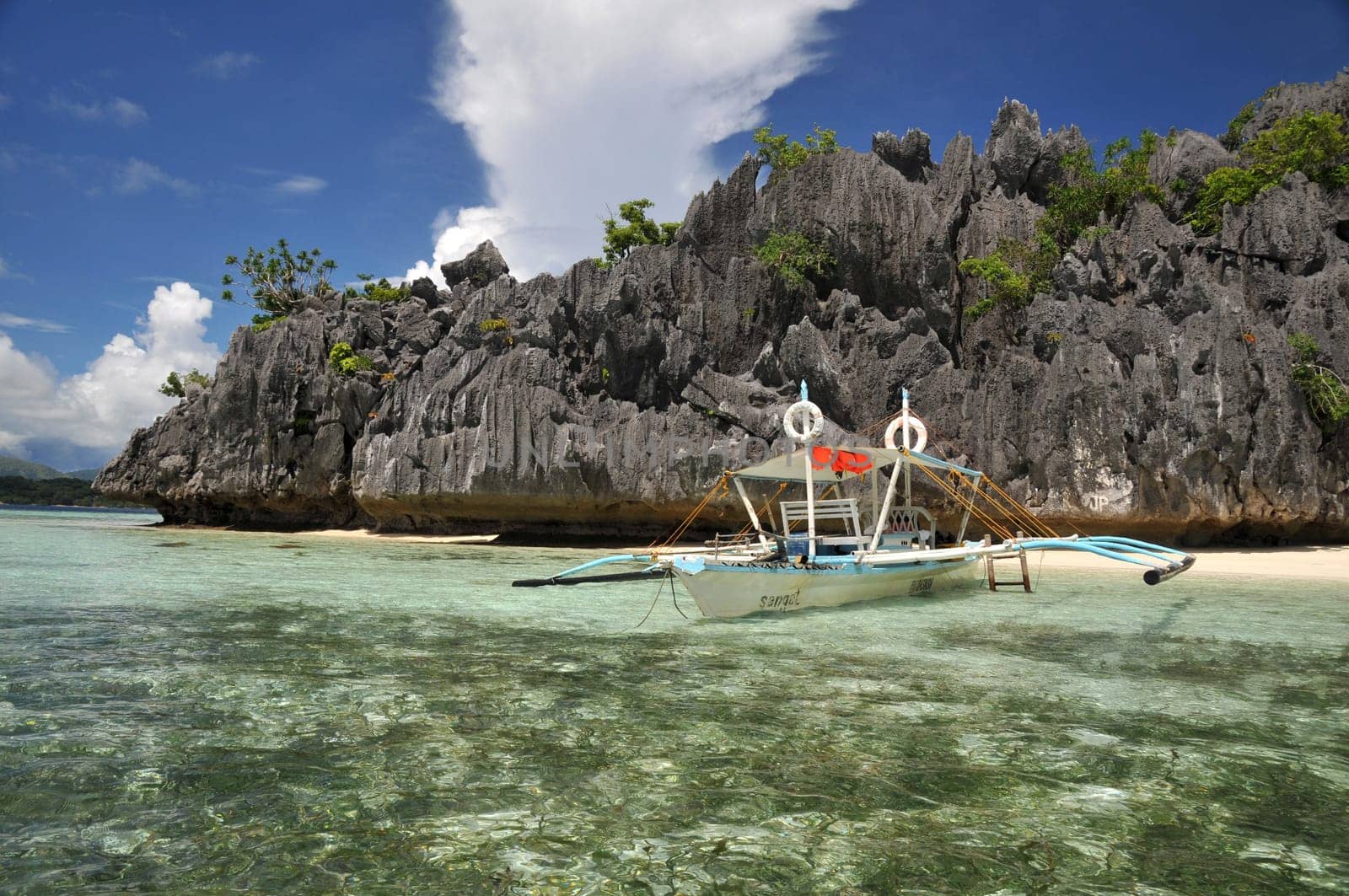 Outrigger boat in front of typical rocky landscape of Palawan / Philippines