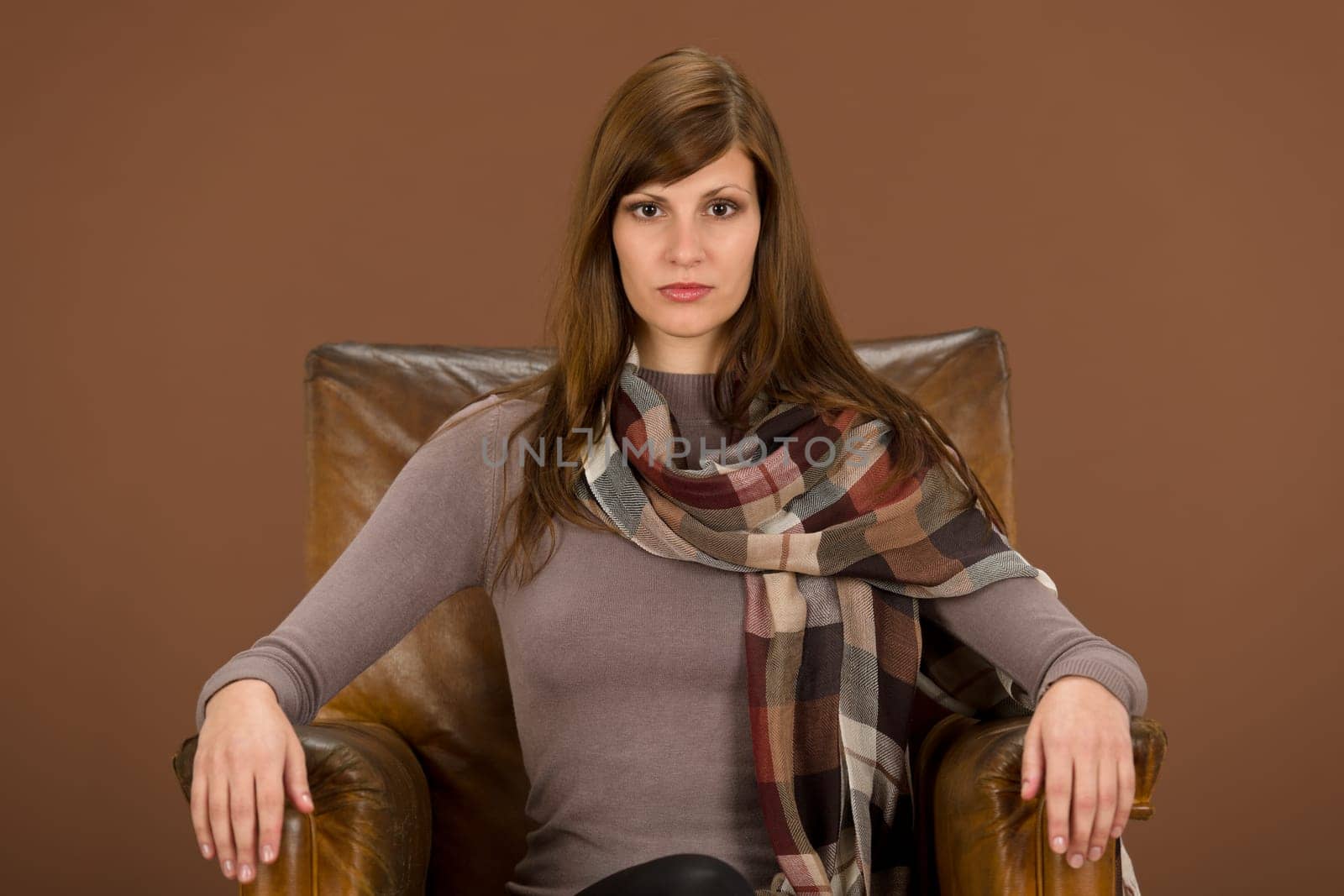 Fashion model on brown leather armchair