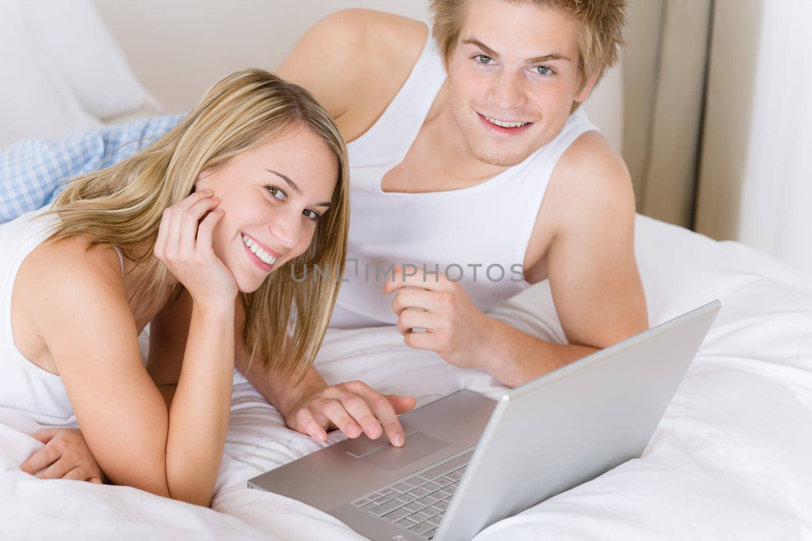 Young couple relax in bed with laptop