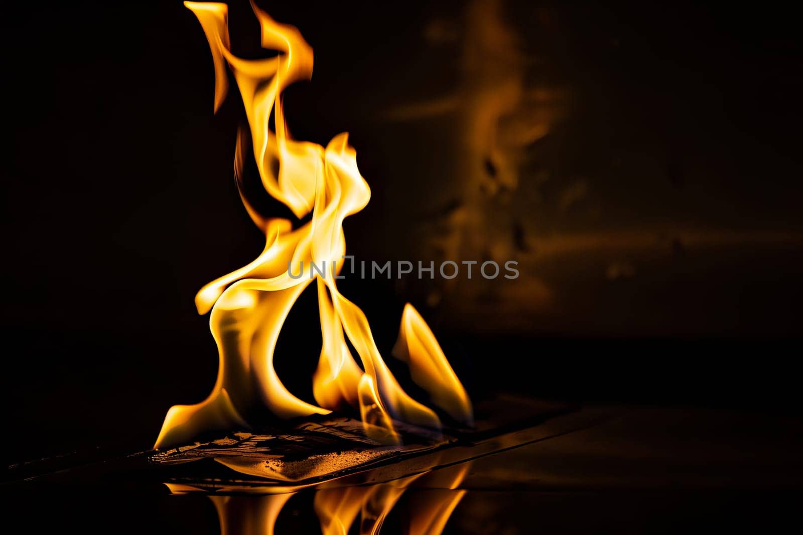 Dramatic flames engulfing paper with fiery glow in dark room.