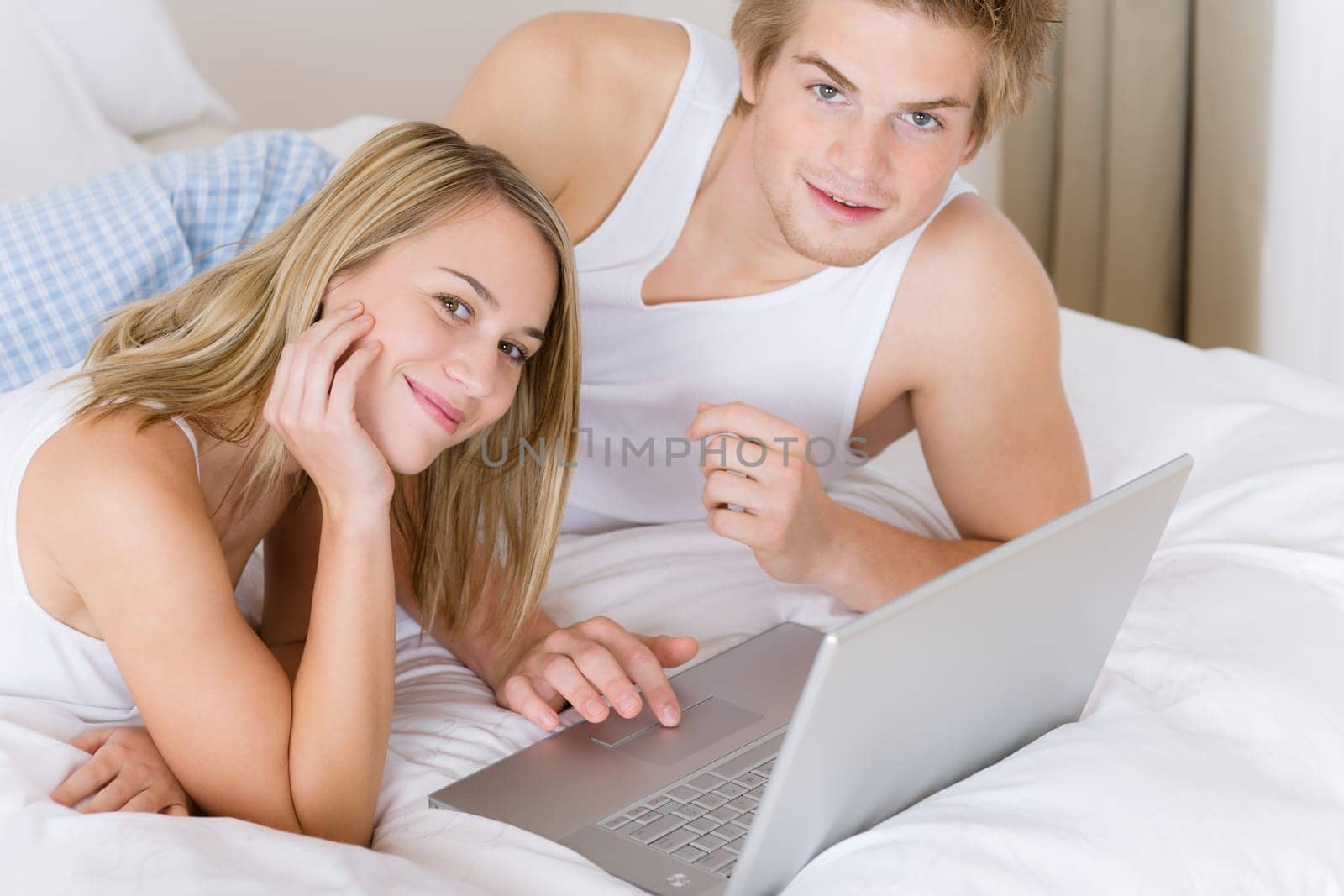 Young couple relax in bed with laptop