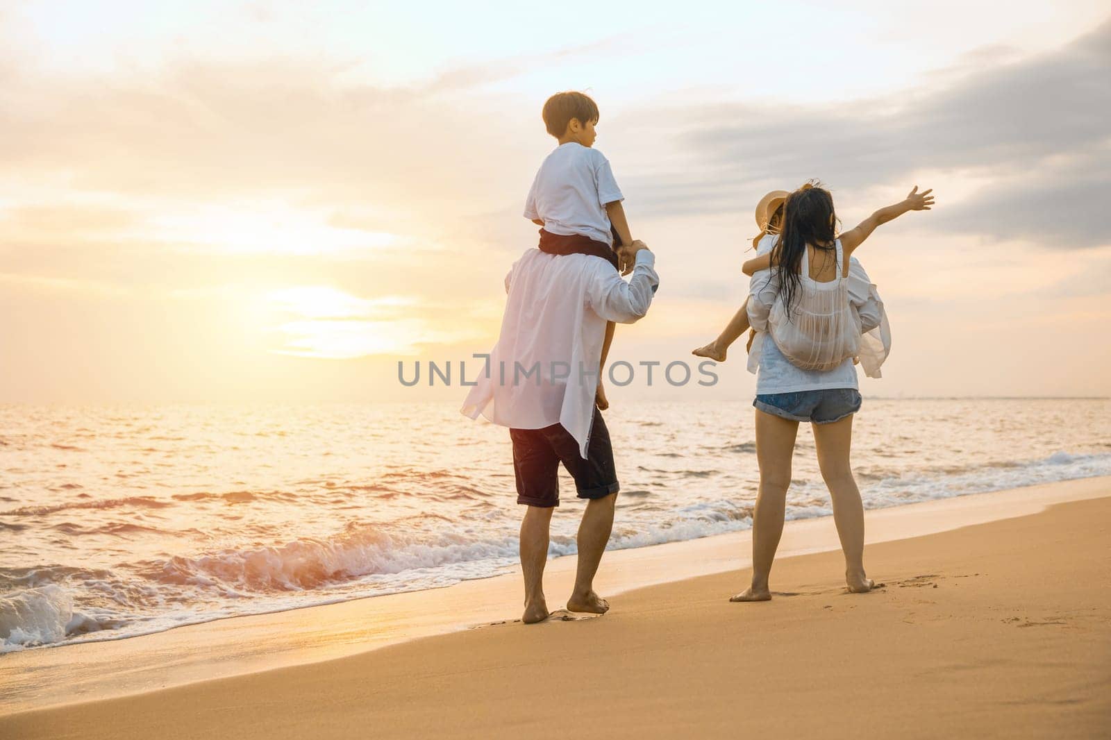 Parents carrying children on shoulders at beach on sunset, Family on holiday summer vacation, sea for love and joy, Father carrying son and Mother carrying daughter on shoulder ride walk summer beach
