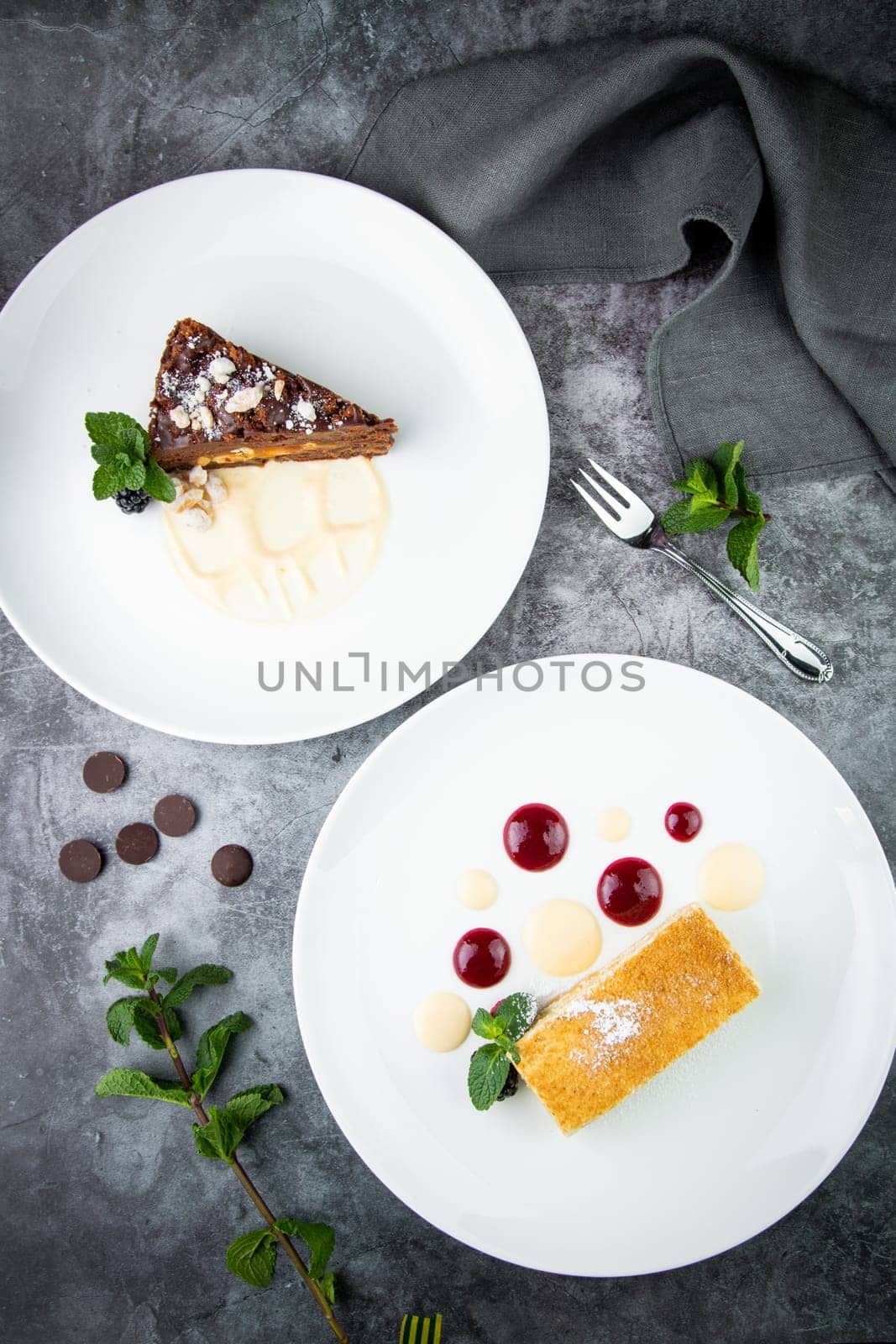 white sponge cake with drops of syrup, mint and wild berries on a round plate top veiw by tewolf