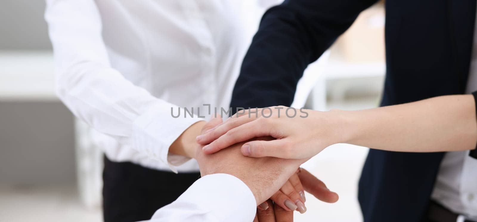 Group of people in suits crossed hands by kuprevich