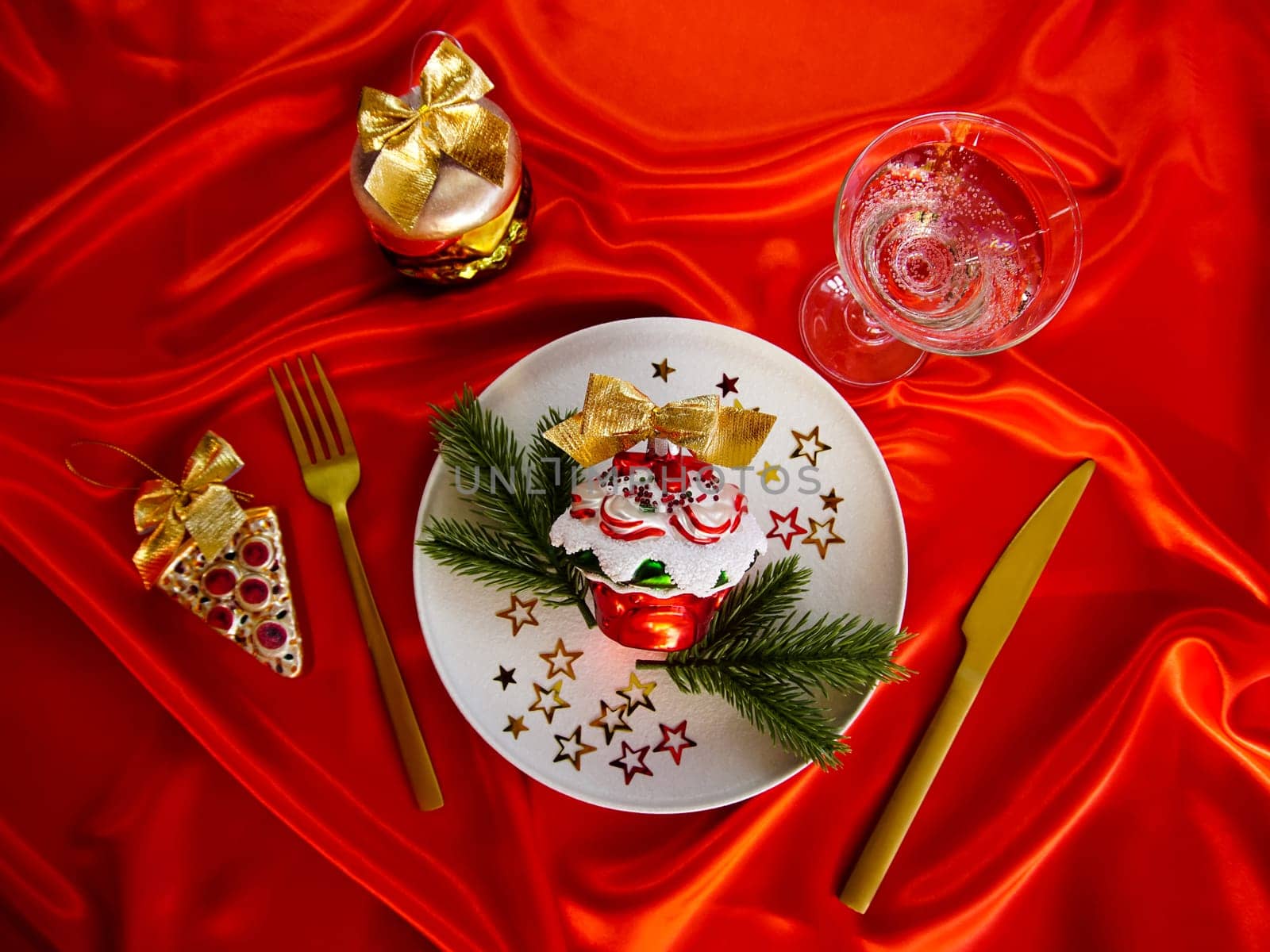 New Year's desserts. Creative table setting with Christmas tree toys. Plates with Christmas toys are placed on a red satin tablecloth.
