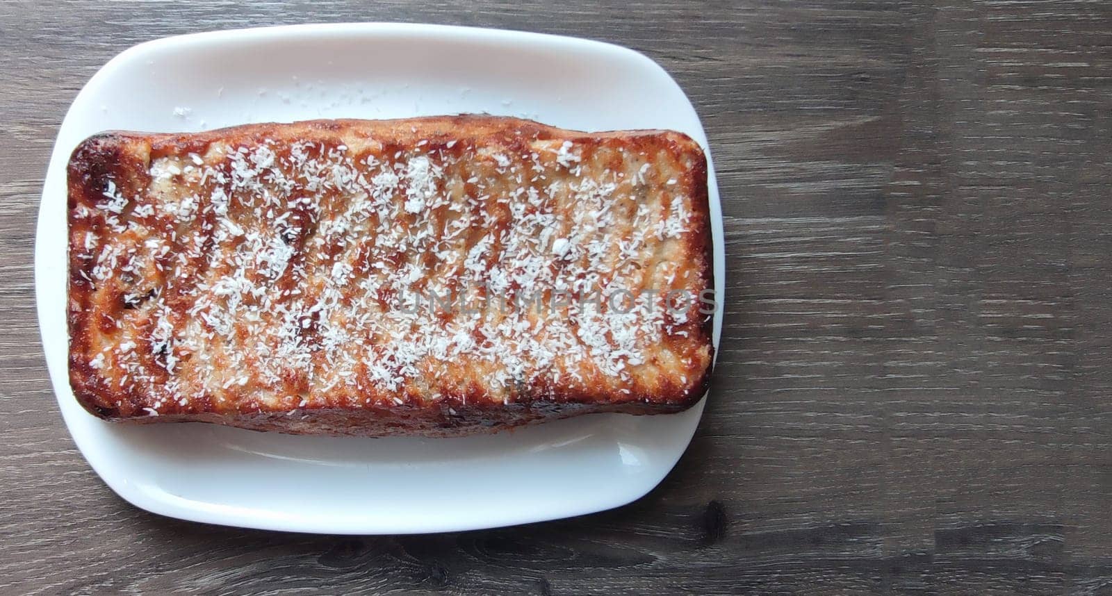 cottage cheese casserole on a white plate on a wooden table, top view, copy space