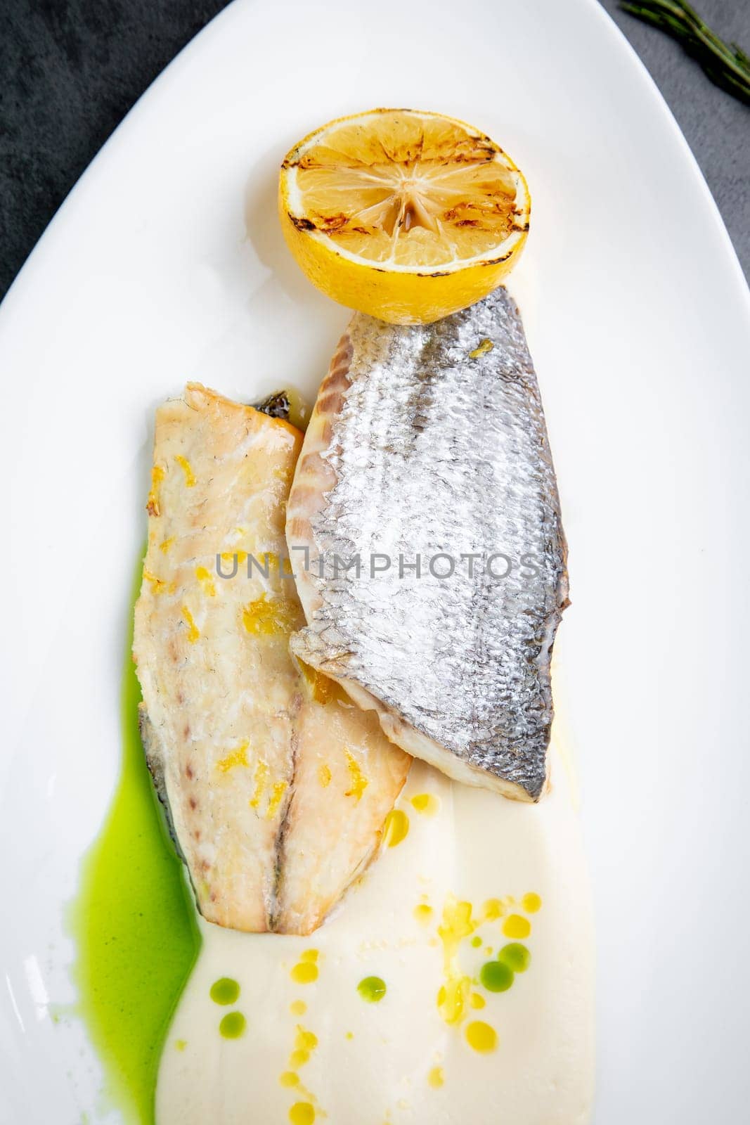 pieces of fried fish with sauce and fried lemon on a white plate side view by tewolf