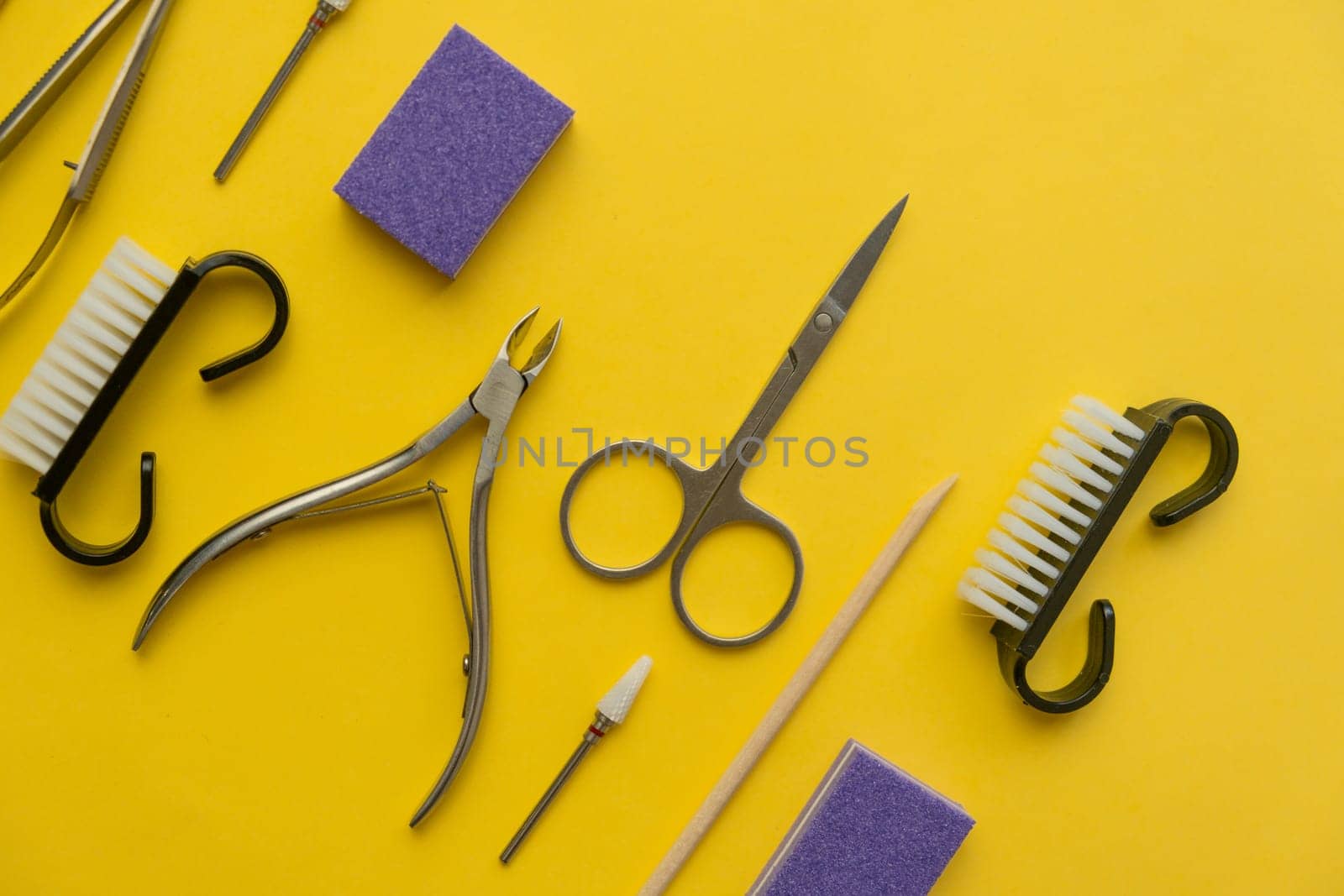 Professional manicure tools on yellow background. Manicure set. Top view. Cuticle pusher, cuticle trimmer and purpose scissor. Set of manicure and pedicure tools and cosmetics with space