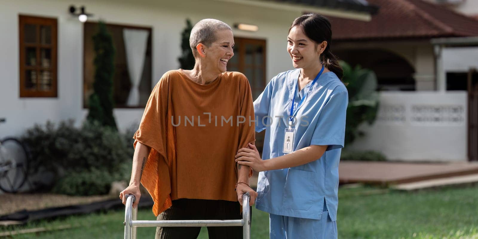 Nurse or caregiver help elderly walk by using walker in garden by itchaznong