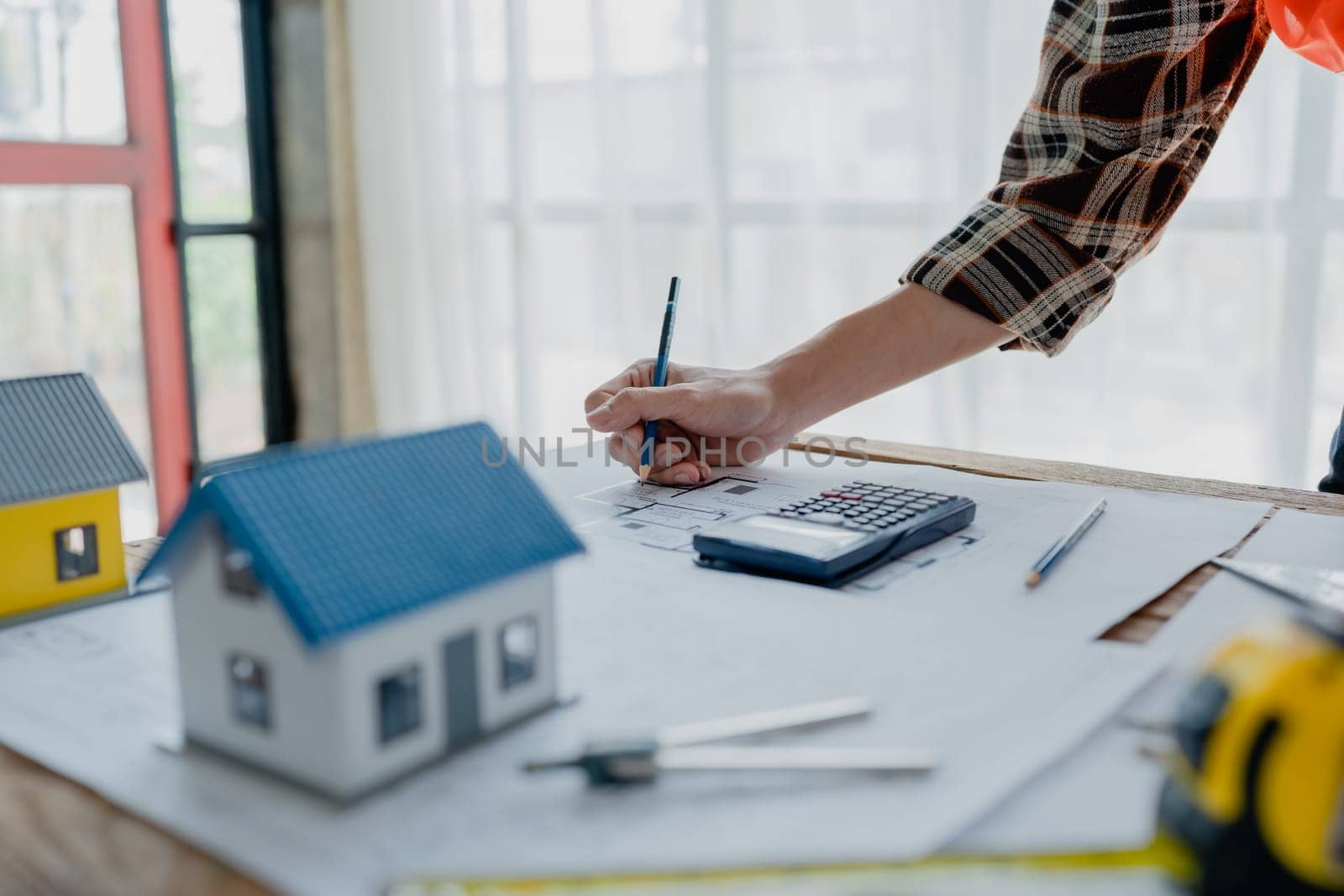 engineer brainstorming and measuring for cost estimating on blueprint and floor plan drawings about design architectural and engineering for houses and buildings by Manastrong