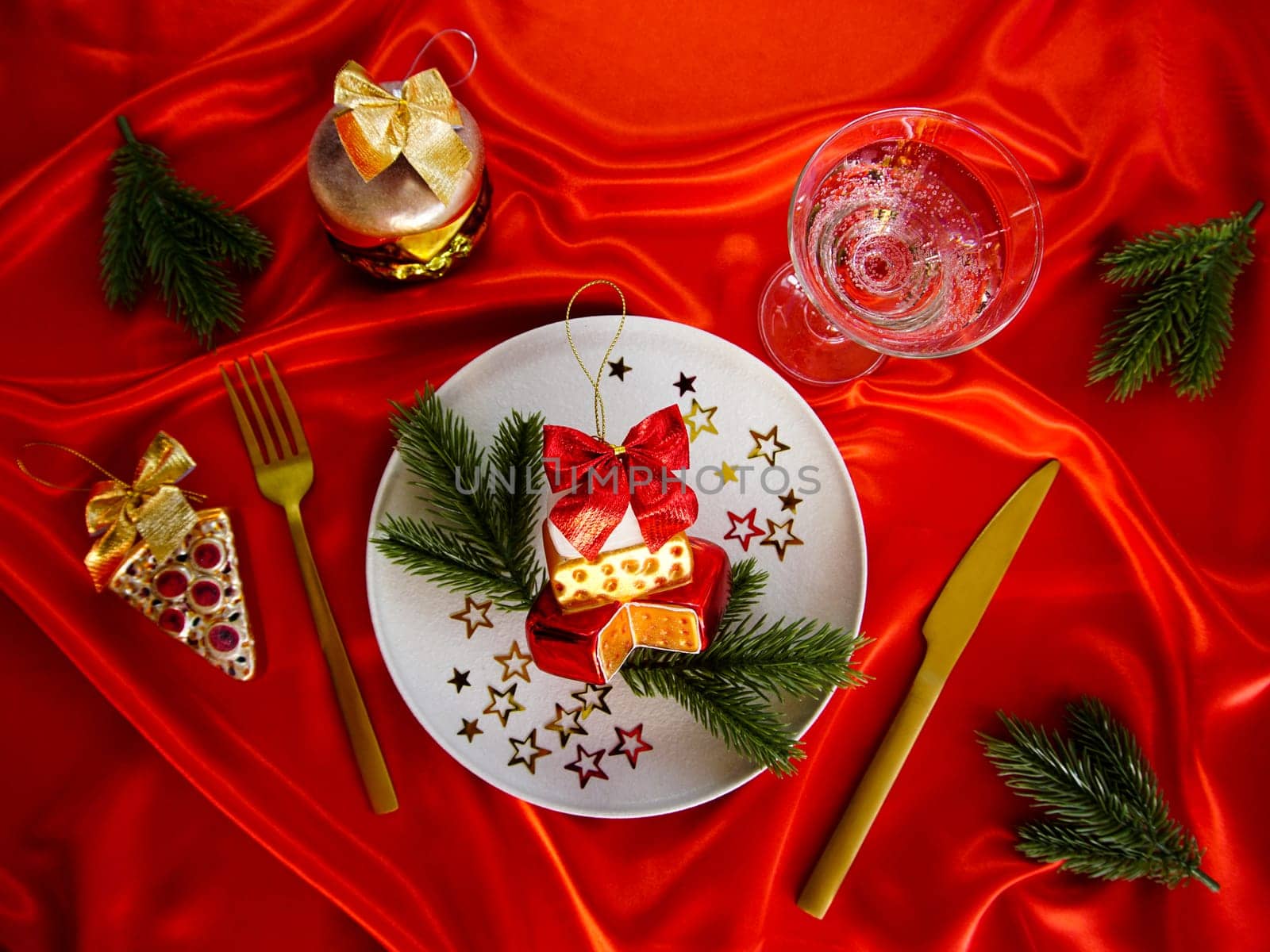 New Year's desserts. Creative table setting with Christmas tree toys. Plates with Christmas toys are placed on a red satin tablecloth.