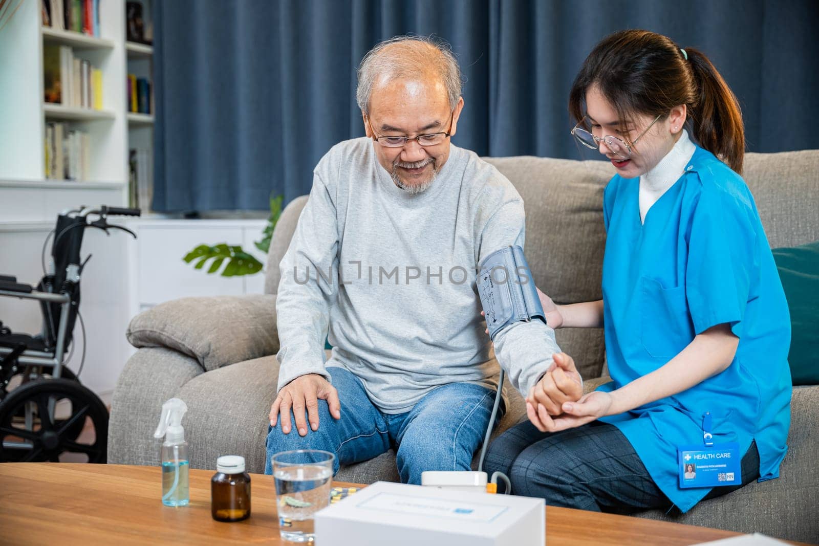 Asian nurse visit patient senior man at home she measuring arterial blood pressure on arm by Sorapop