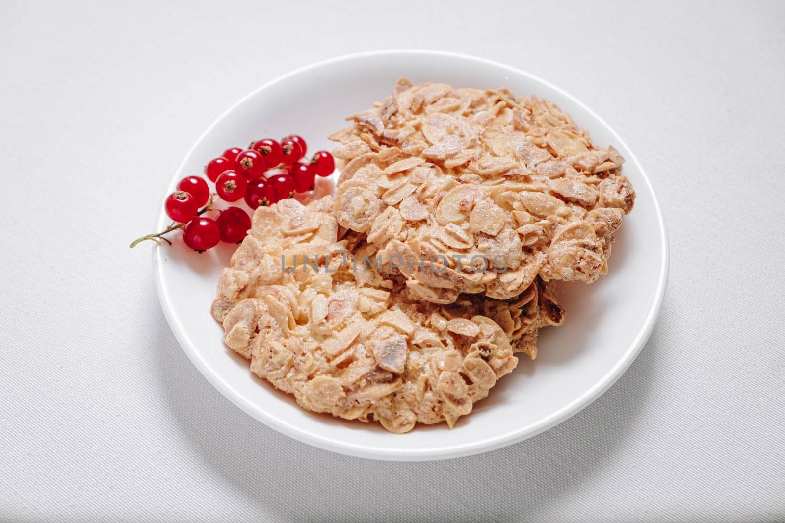 whole grain cookies with a sprig of red currants in a small white plate side view by tewolf