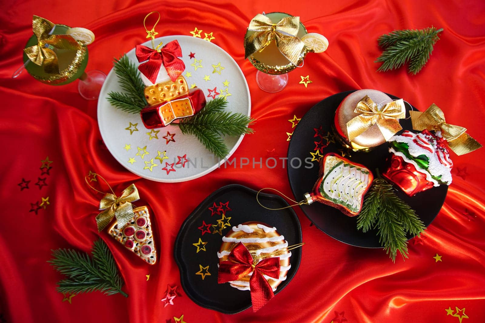 New Year's desserts. Creative table setting with Christmas tree toys. Plates with Christmas toys are placed on a red satin tablecloth.