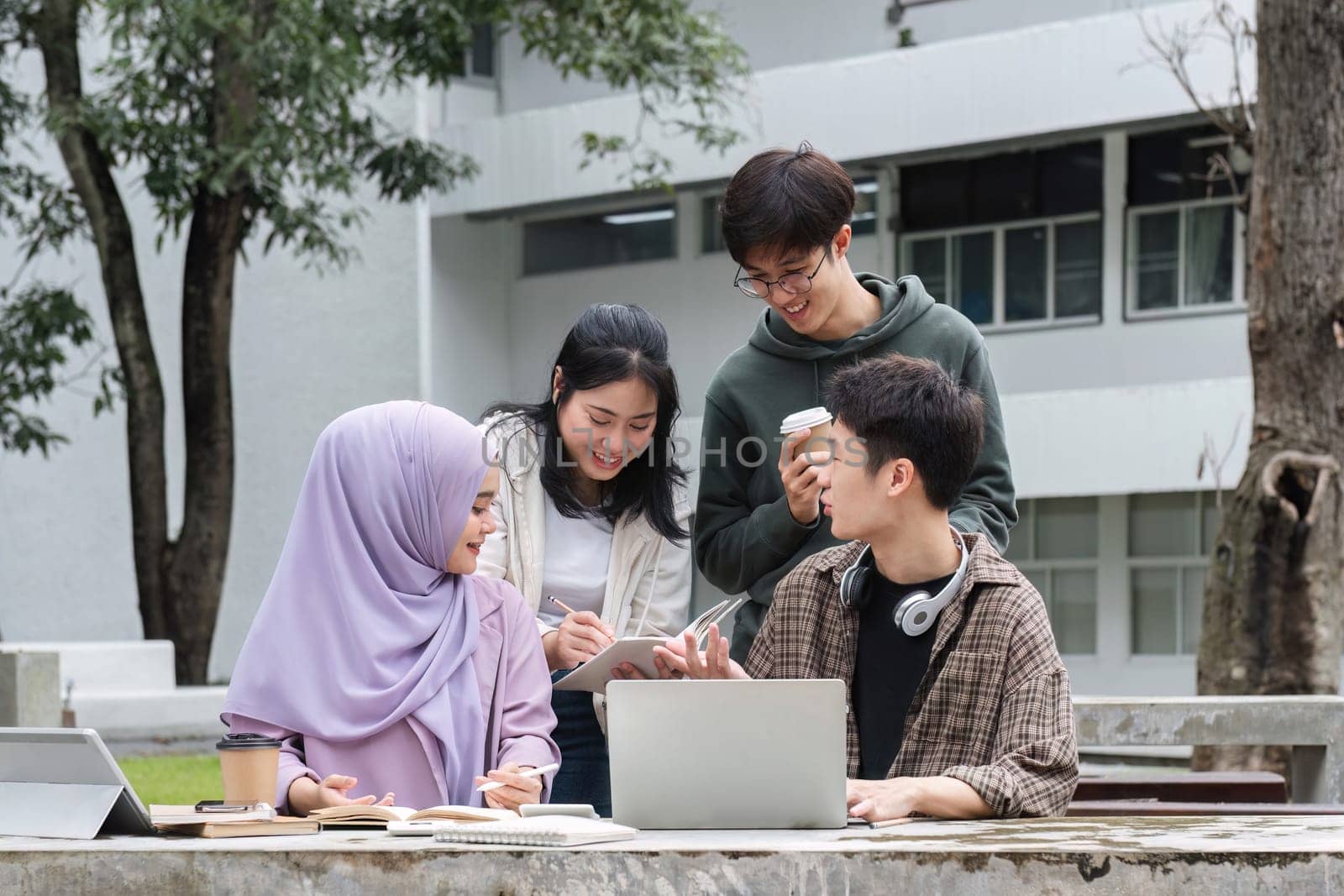 A multiracial group of students at the college, including Muslim and Asian students, sat on benches in a campus break area. Read books or study for exams together. by wichayada