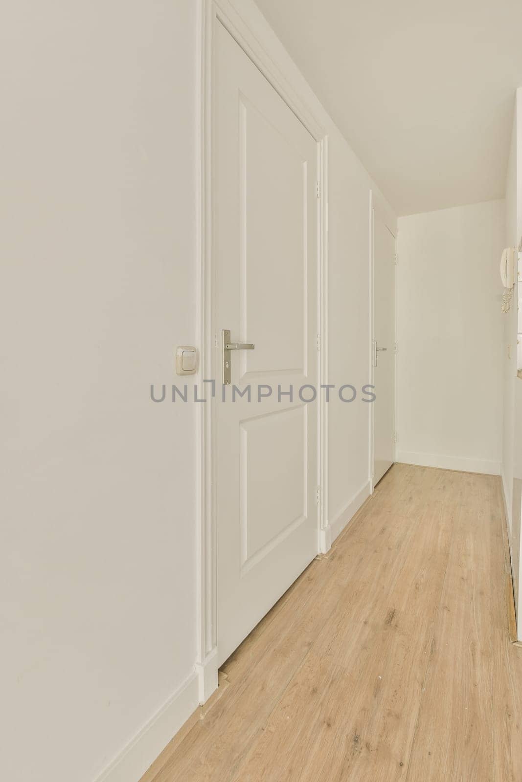 an empty room with white walls and wood flooring on the right side of the room, there is a door leading to another