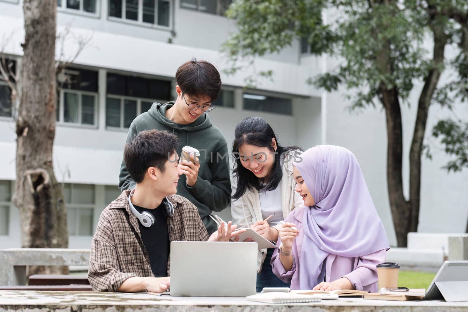 A multiracial group of students at the college, including Muslim and Asian students, sat on benches in a campus break area. Read books or study for exams together. by wichayada