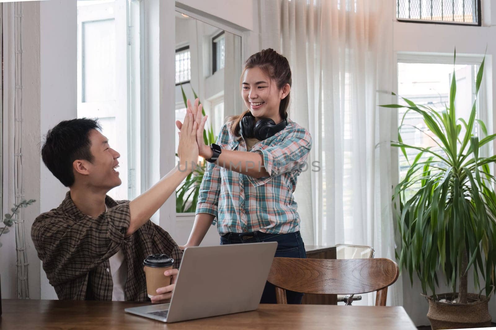 cheerful and happy young Asian friends are gathering together to celebrate the success of a project together in a conference room..