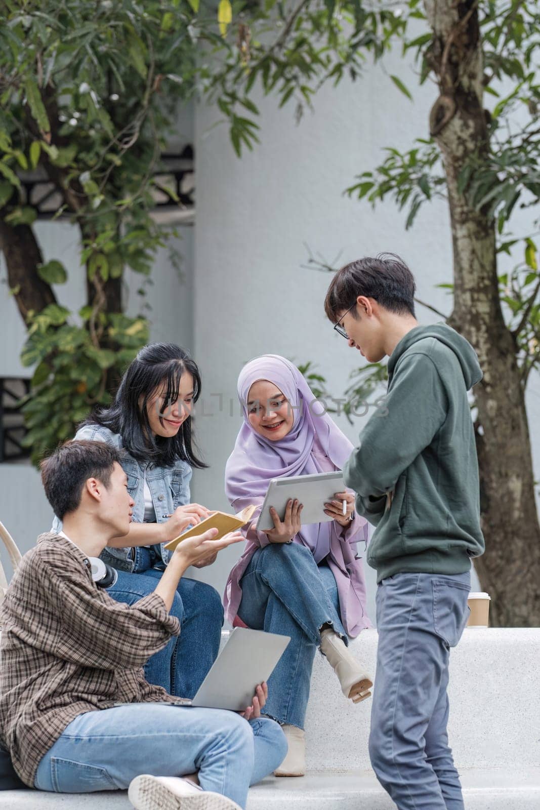Group of Asian college student reading books and tutoring special class for exam on grass field at outdoors. Happiness and Education learning concept. Back to school concept. Teen and people theme..