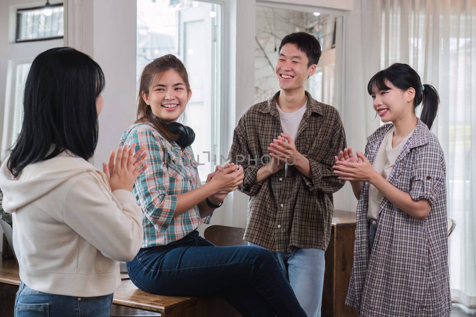 A successful businesswoman sits at a table and is surrounded by congratulating co-workers standing and applauding. by wichayada