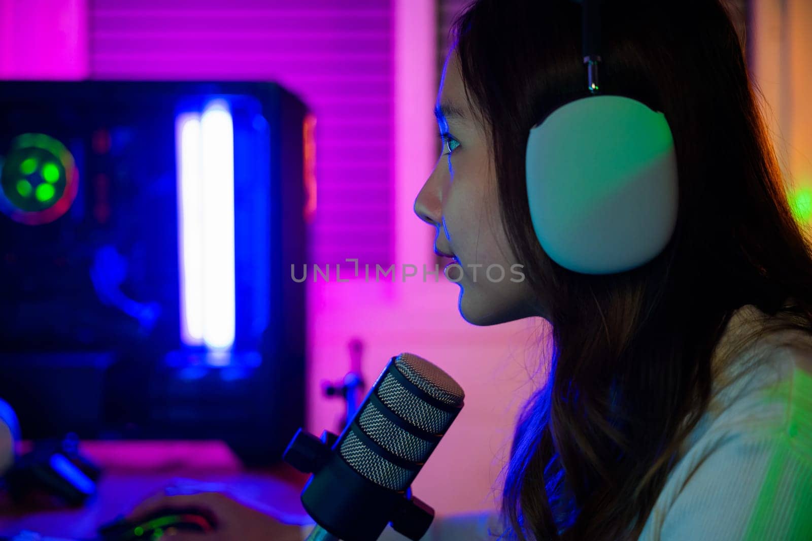 Asian young gamer woman playing video games online on computer she live stream and chat with fans, Happy streamer female talking with microphone in gaming room, game streaming concept