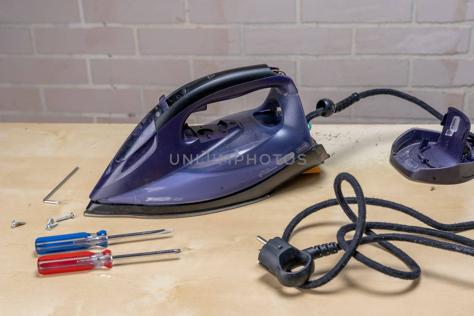 Disassembled electric iron. repairman checking and fixing broken iron. repairman checking and fixing broken steam ironusing simple tools. closeup