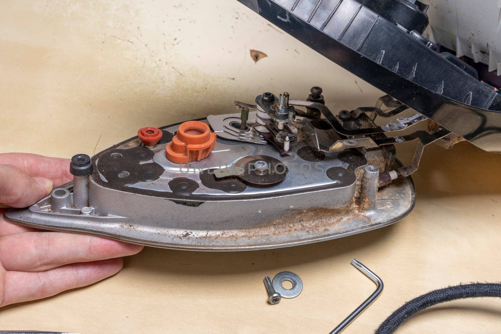 Disassembled electric iron. repairman checking and fixing broken iron. repairman checking and fixing broken steam ironusing simple tools. closeup