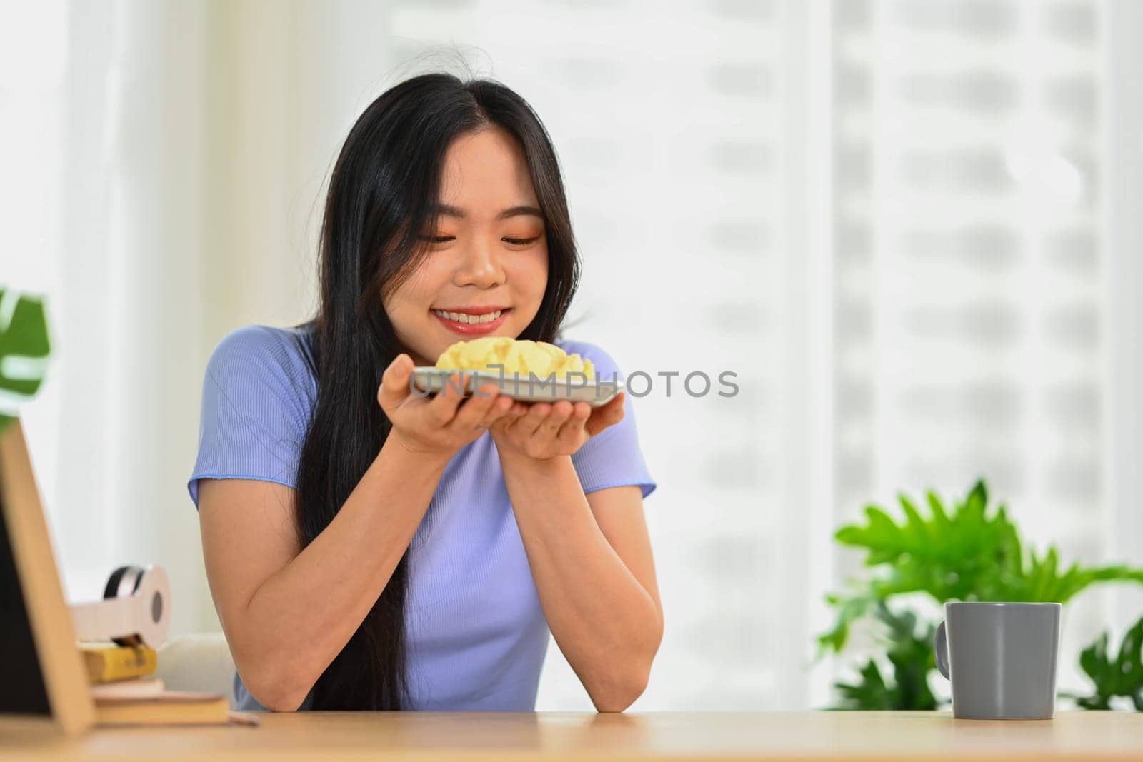 Shot of happy young woman eating homemade cream puff. People, food and lifestyle concept by prathanchorruangsak