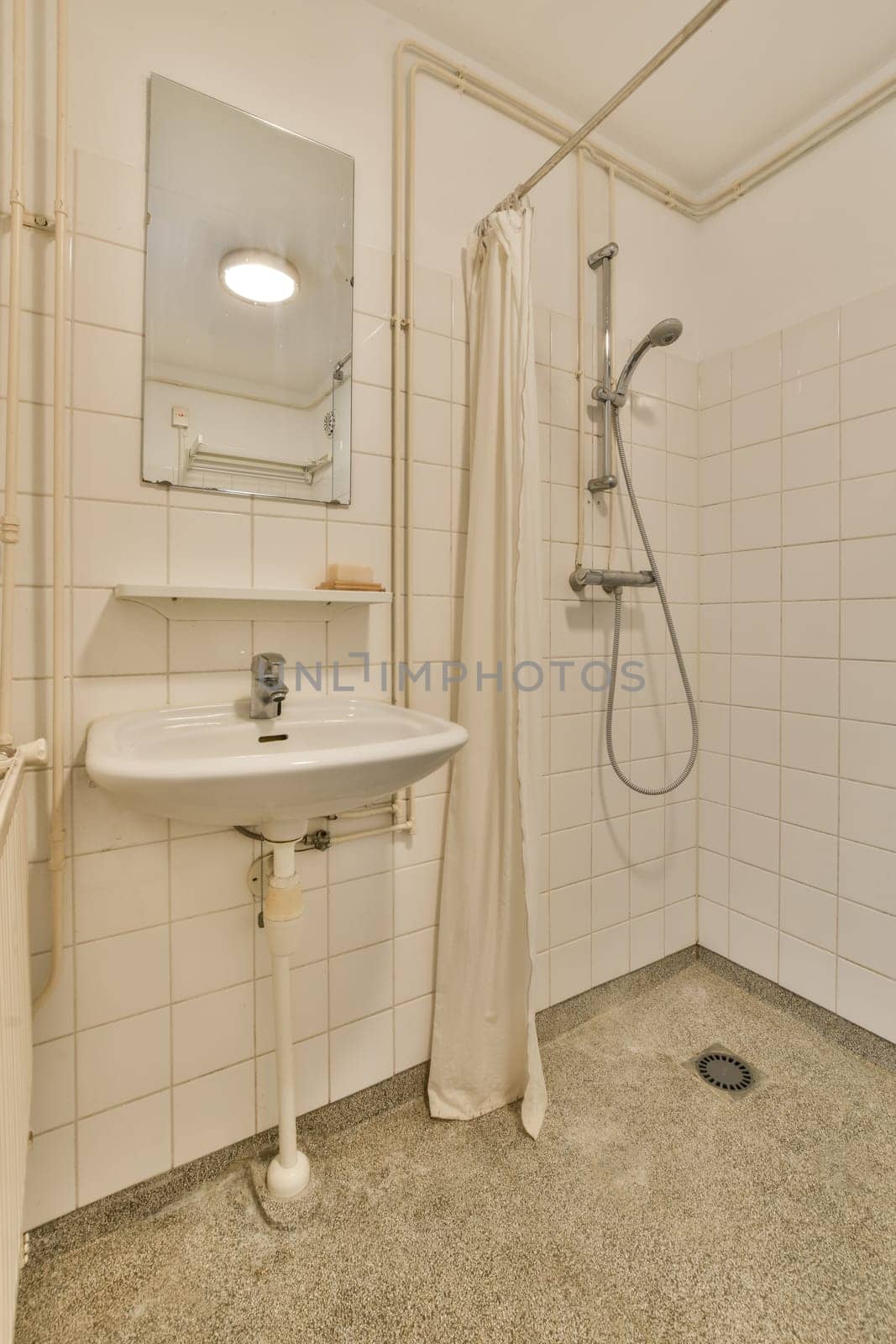 a bathroom with a sink, mirror and shower head mounted on the wall in it's corner to the right