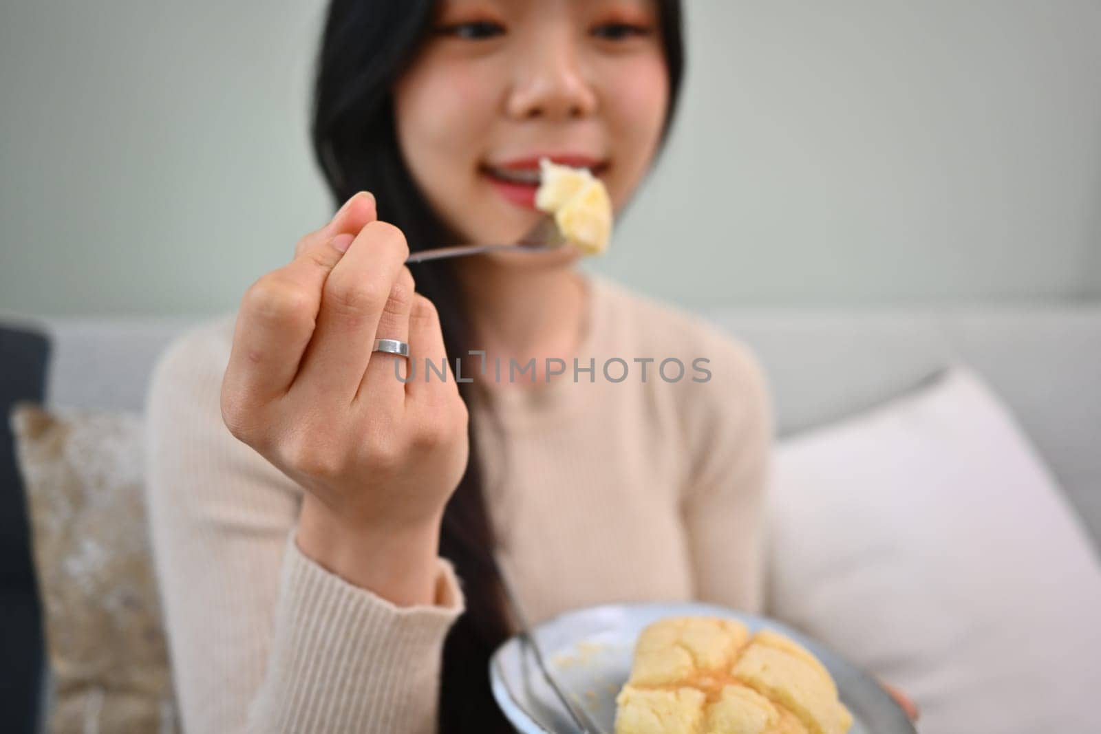 Shot of happy young woman eating homemade cream puff. People, food and lifestyle concept by prathanchorruangsak