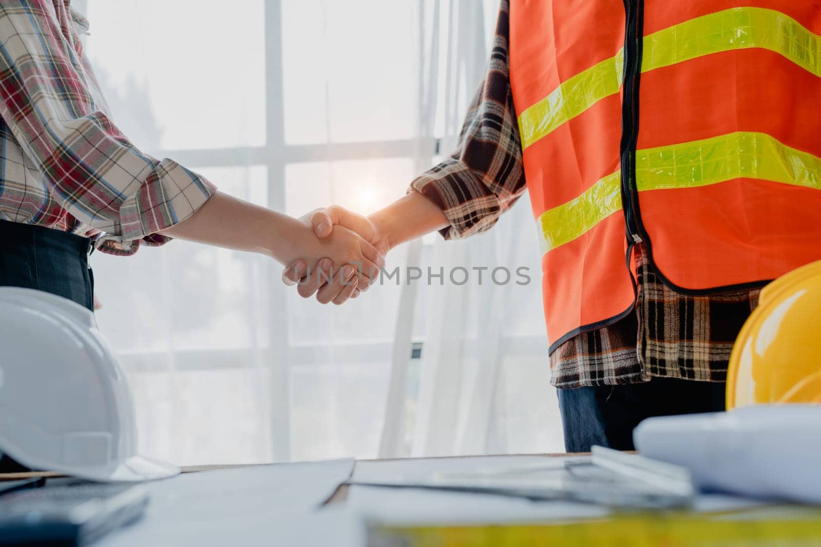 Engineers, designers and interior designers are handshake shack hands deal finalizing the design of interiors by discussing selecting materials and colors to design rooms to present to clients. by Manastrong