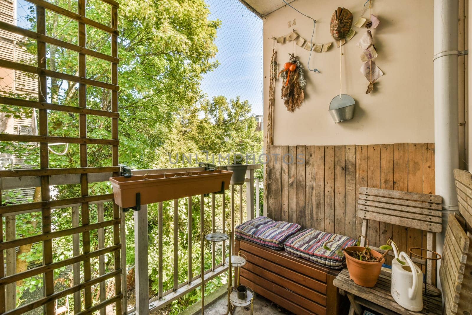 an outside area with a bench and pots hanging on the wall next to it, in front of a wooden fence