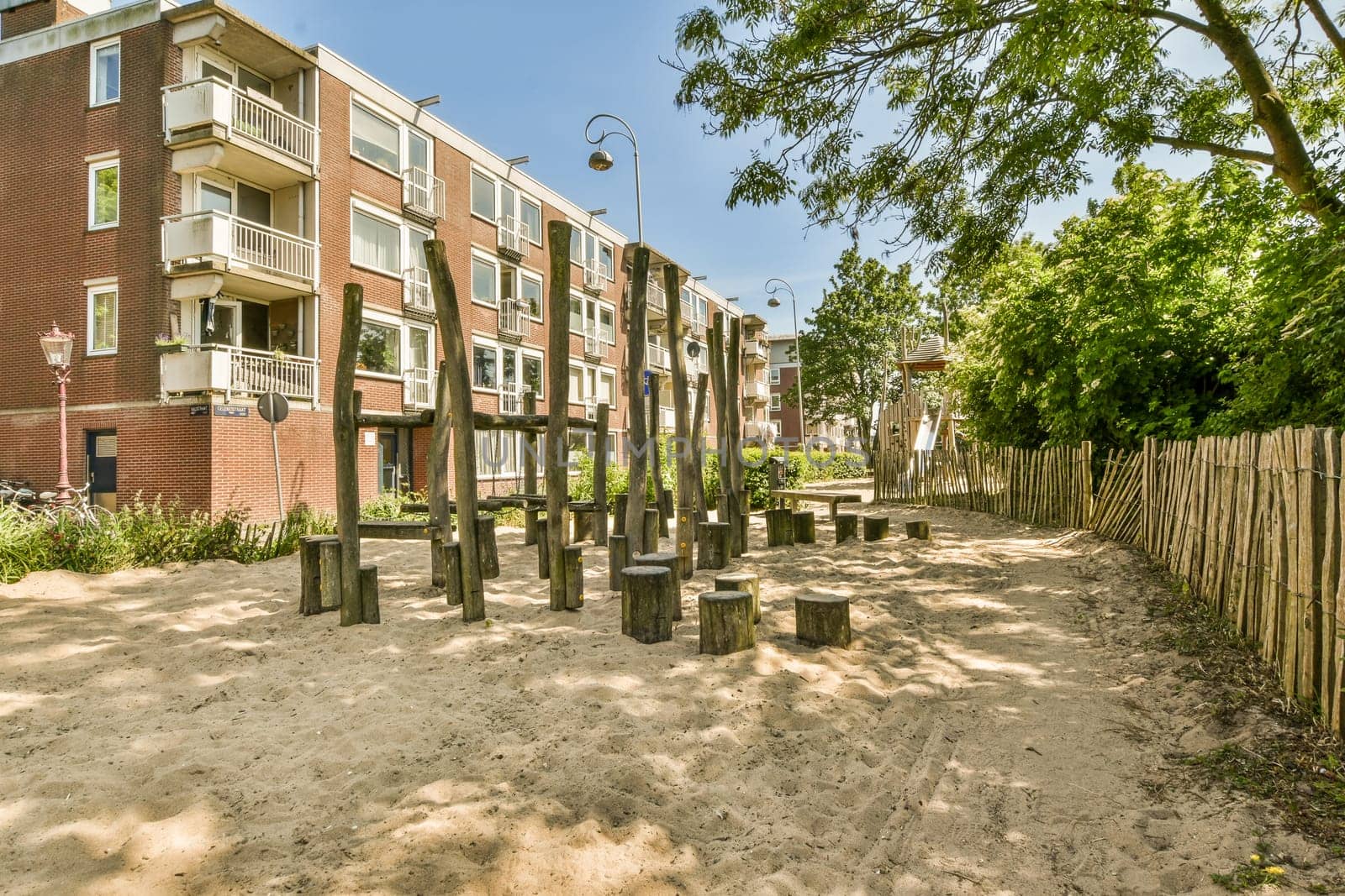 a sandy area with wooden posts in front of apartment by casamedia