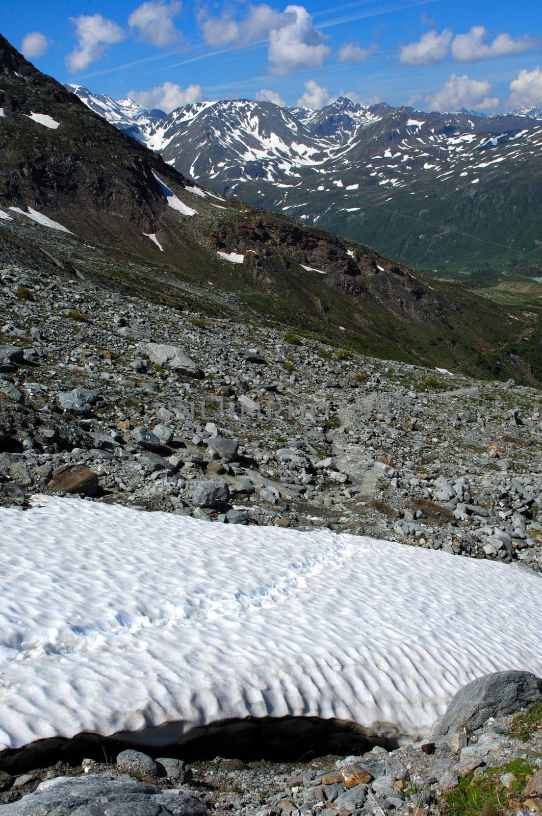 Dangerous snowfield with footprints in the mountains in spring