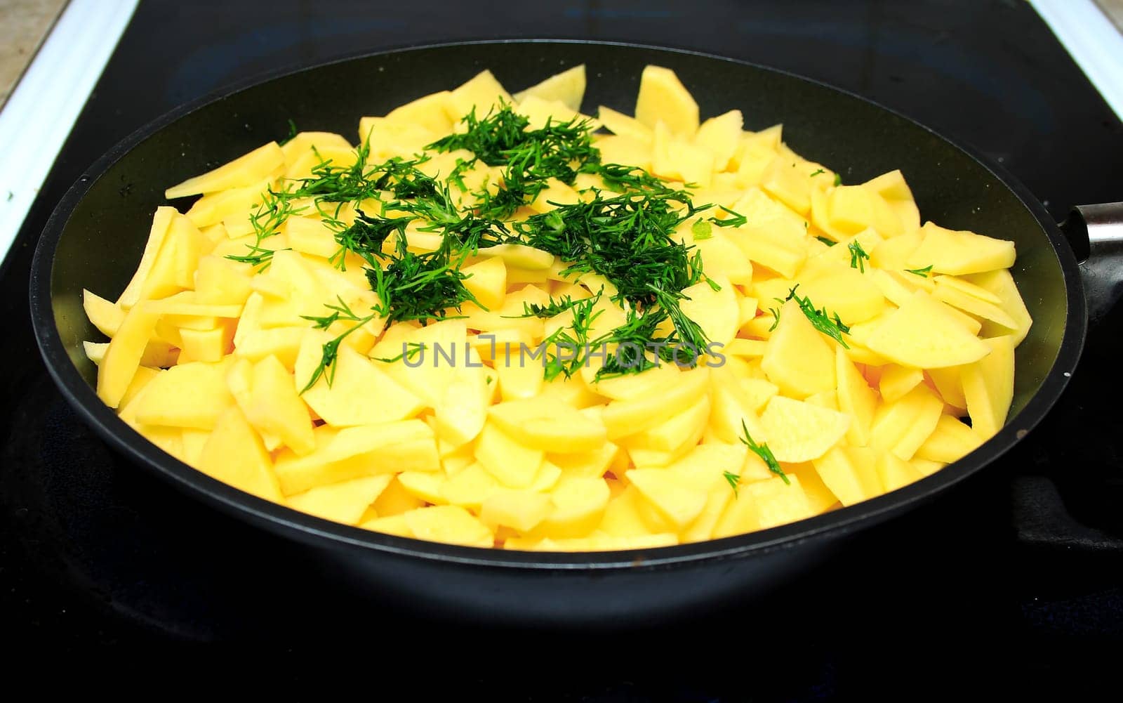Sliced raw potatoes on frying pan