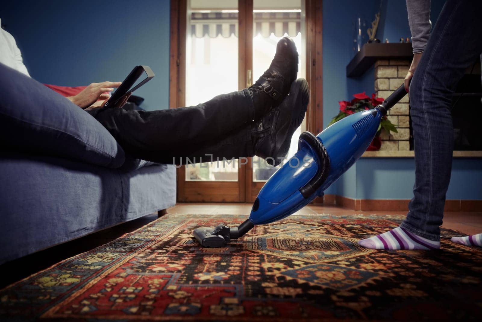 man relaxing while woman doing chores at