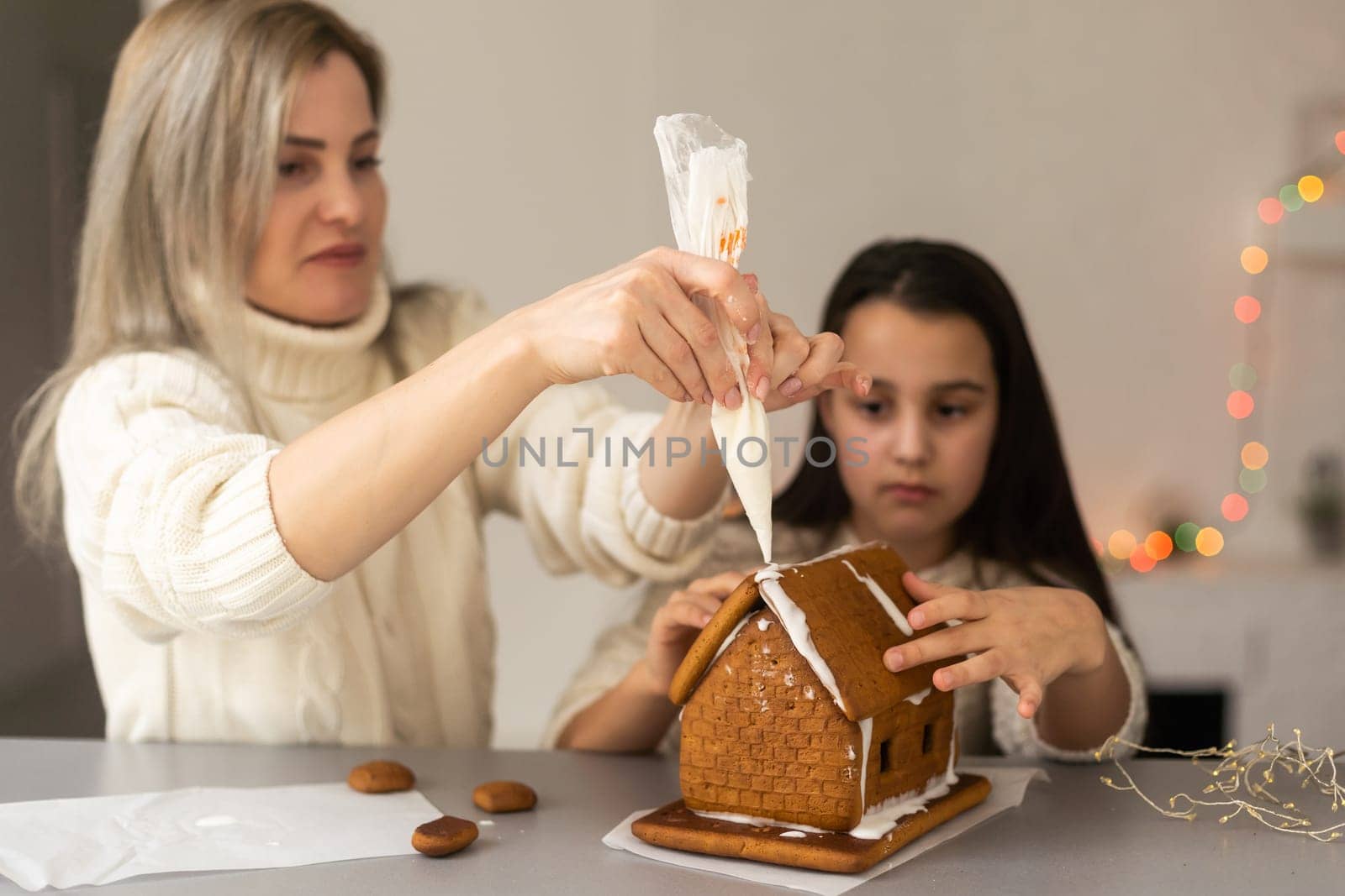 Mother and daughter making gingerbread cookies house, decorating at home, Christmas concept by Andelov13