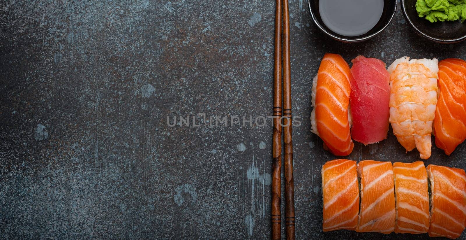 Set of traditional Japanese sushi and rolls top view with soy sauce and chopsticks on rustic stone background. Sushi with salmon, tuna and shrimp, space for text by its_al_dente