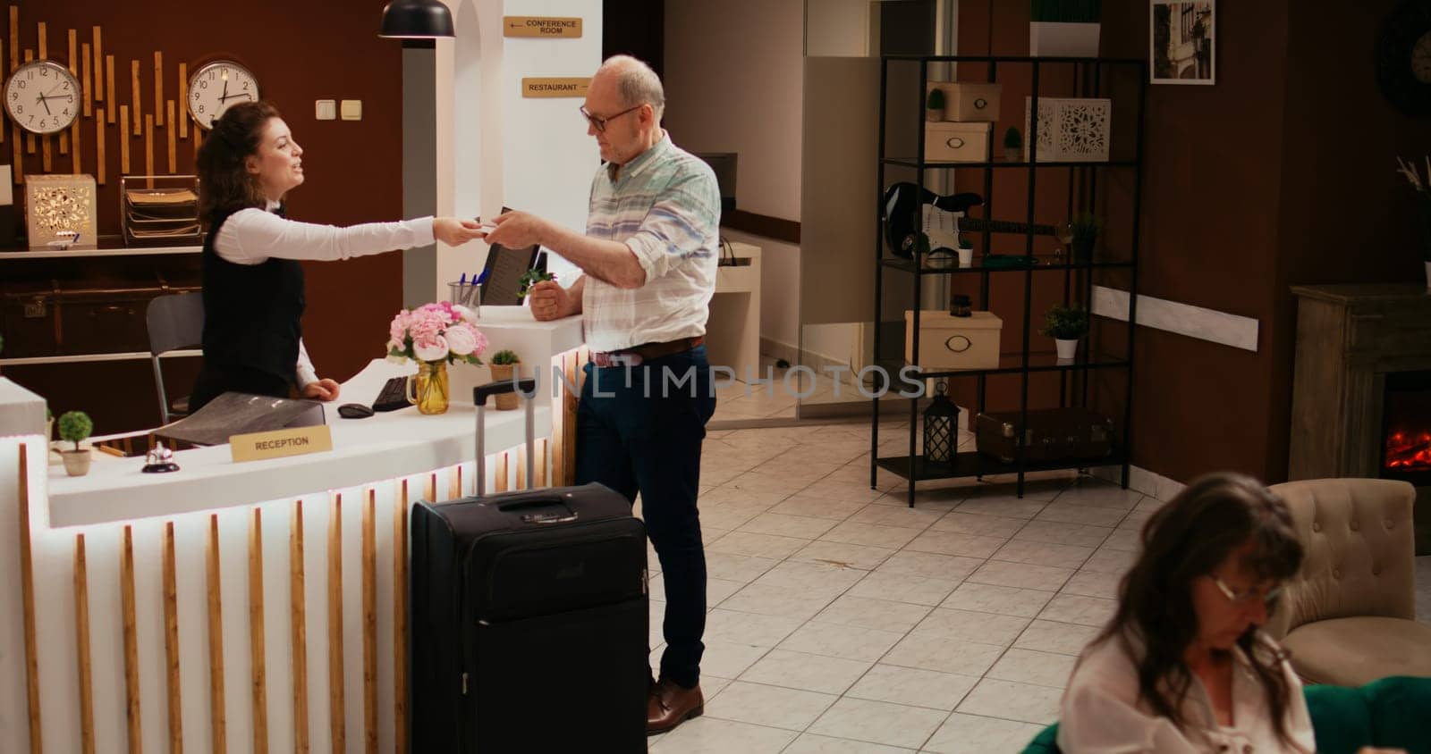 Hotel worker giving room key card for access to senior tourist, signing up for all inclusive service during his stay at resort. Happy person travelling on retirement holiday, front desk staff.