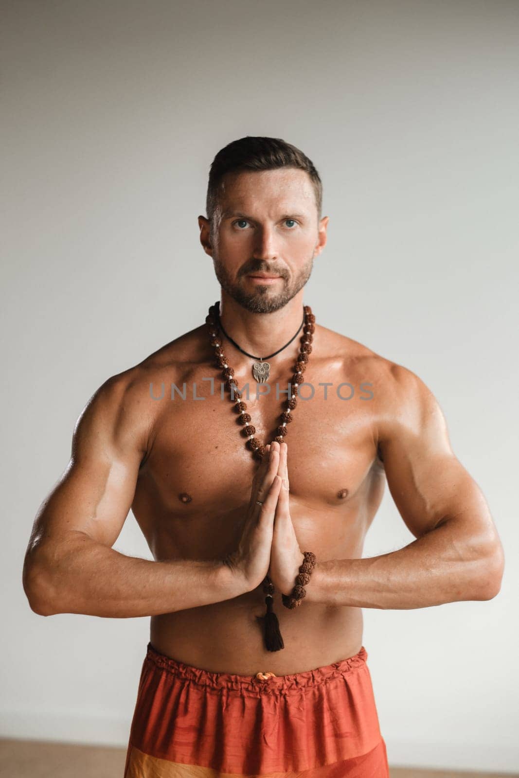 A muscular man with a bare torso and an amulet is standing in the room.