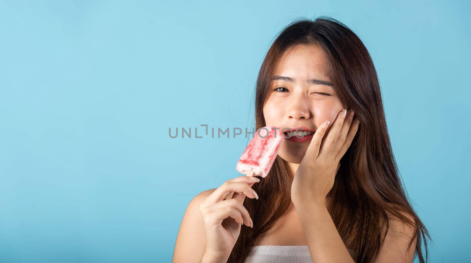 Portrait of Asian young woman with sensitive teeth after eating delicious ice cream by Sorapop