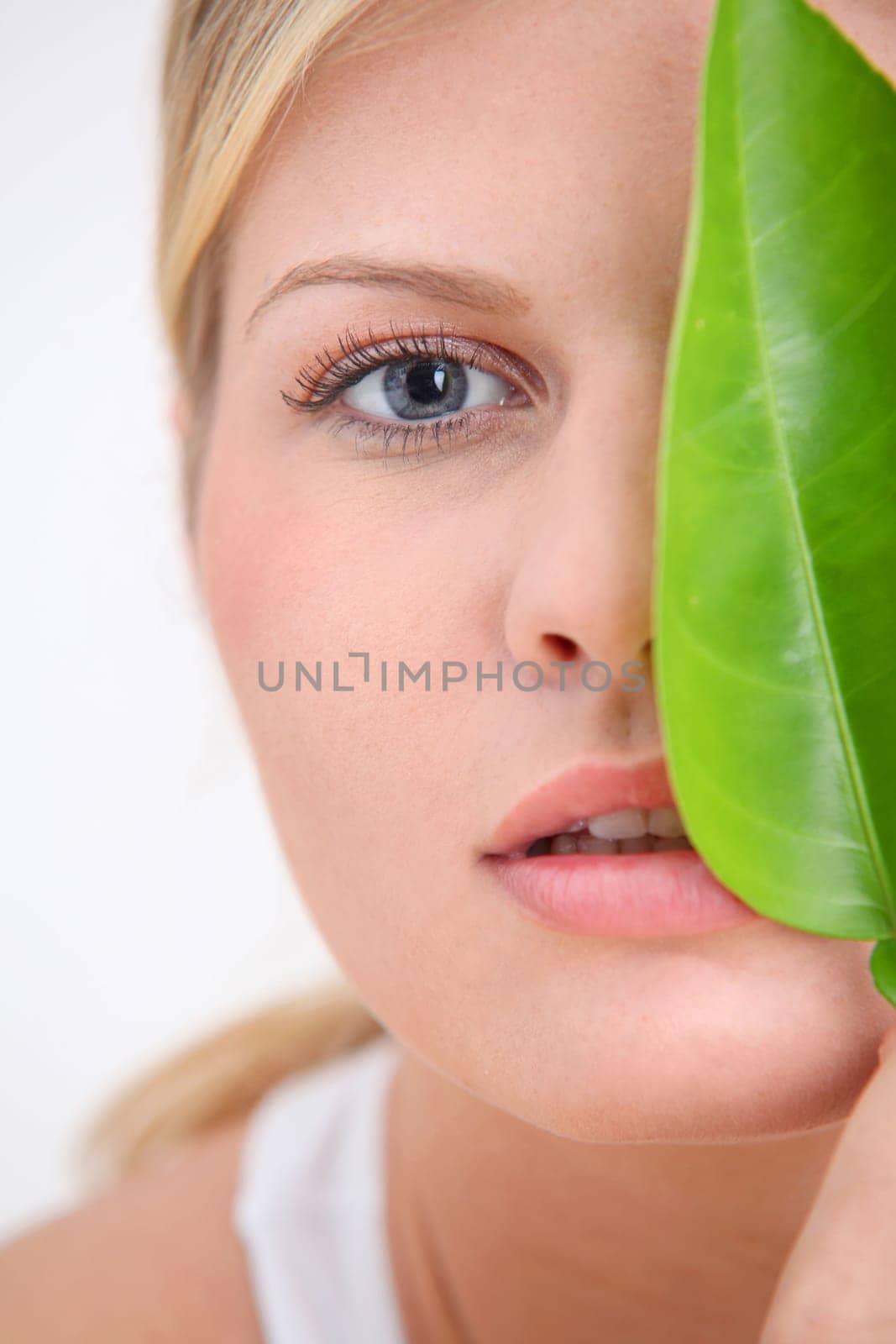 Closeup of beautiful woman holding green plant leaf