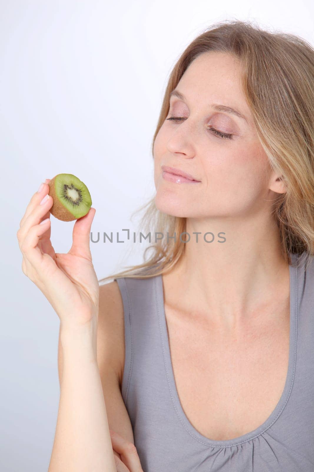 Beautiful blond woman eating kiwis