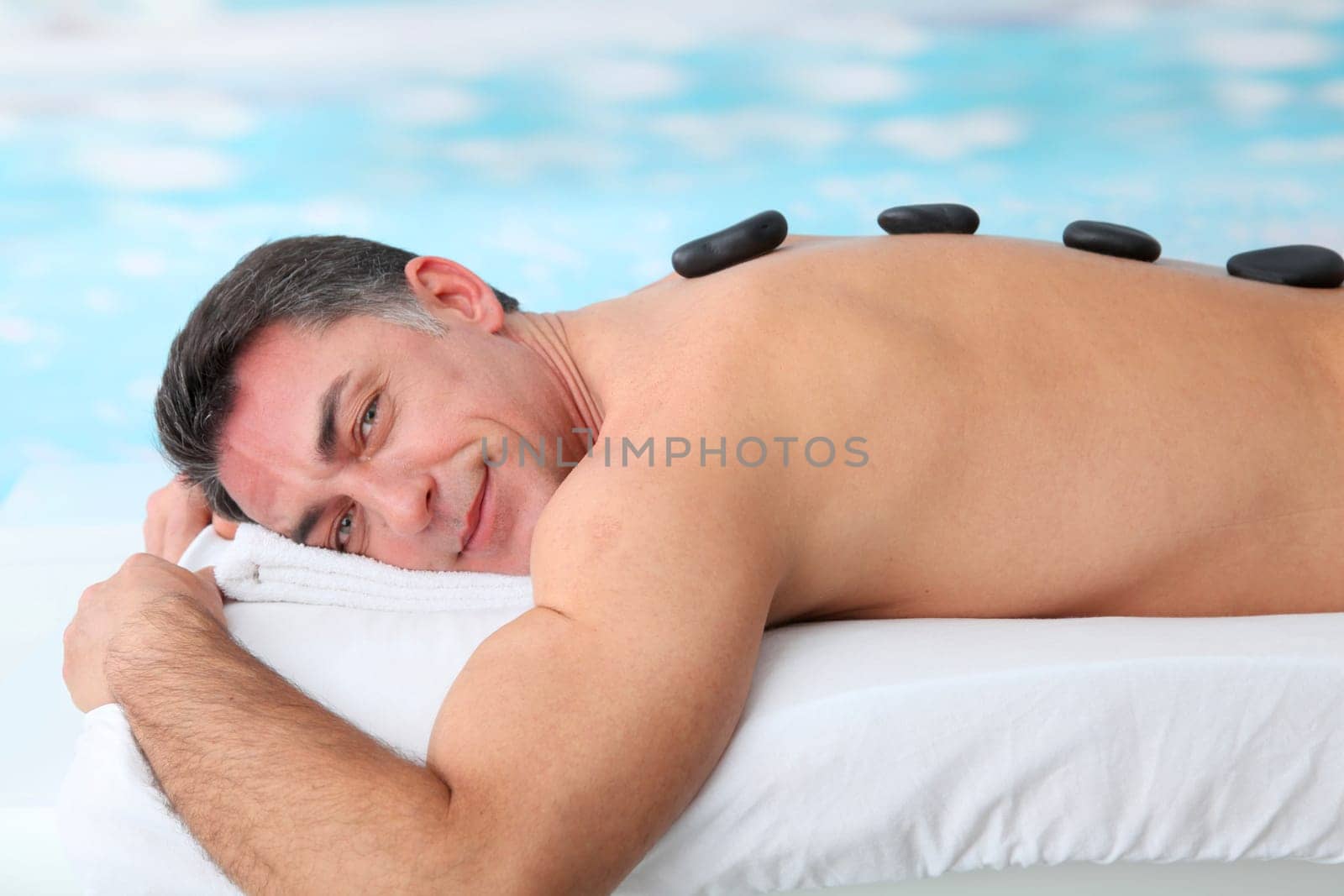 Man laying on massage bed with hot stones