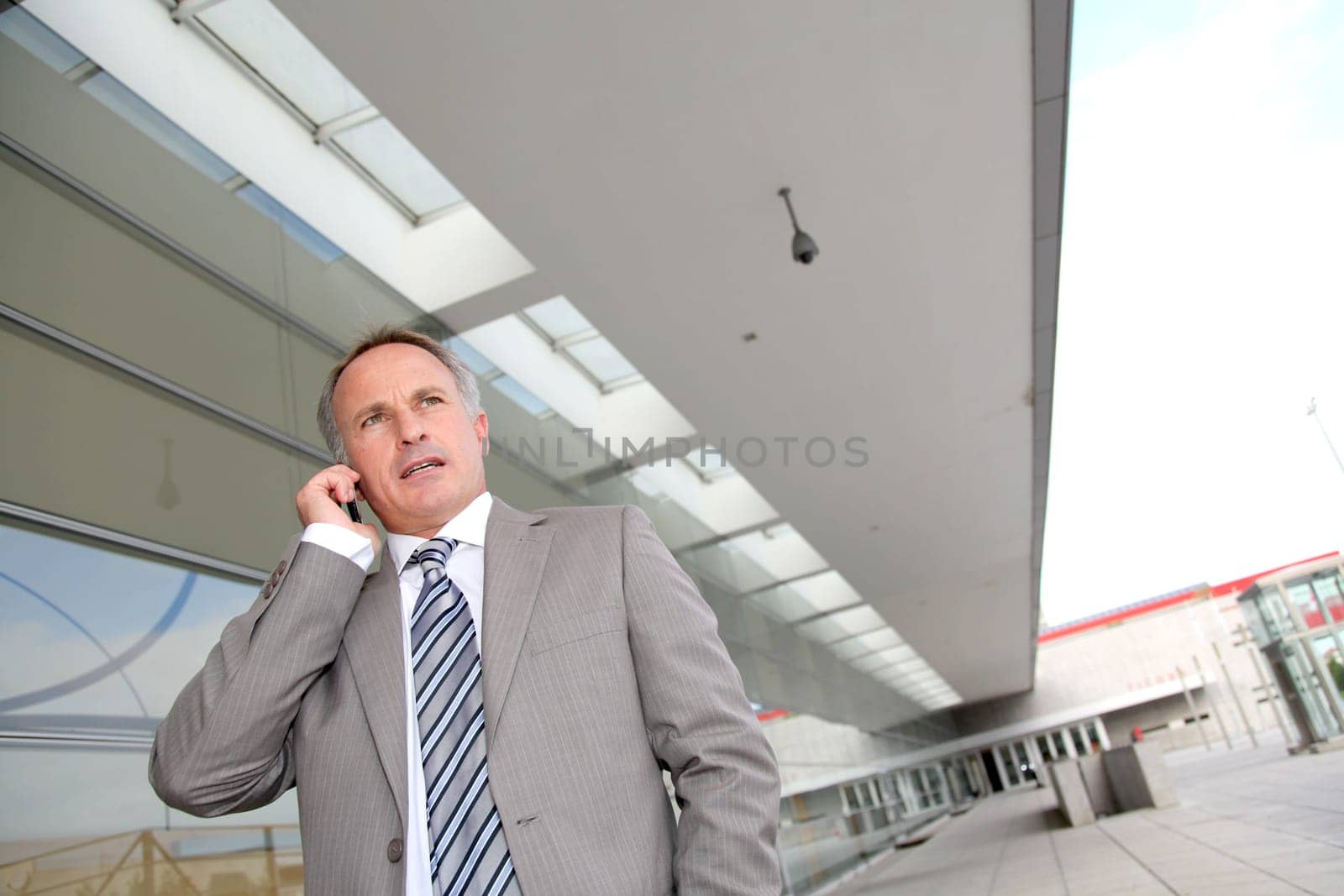 Businessman with mobile phone in front of modern building