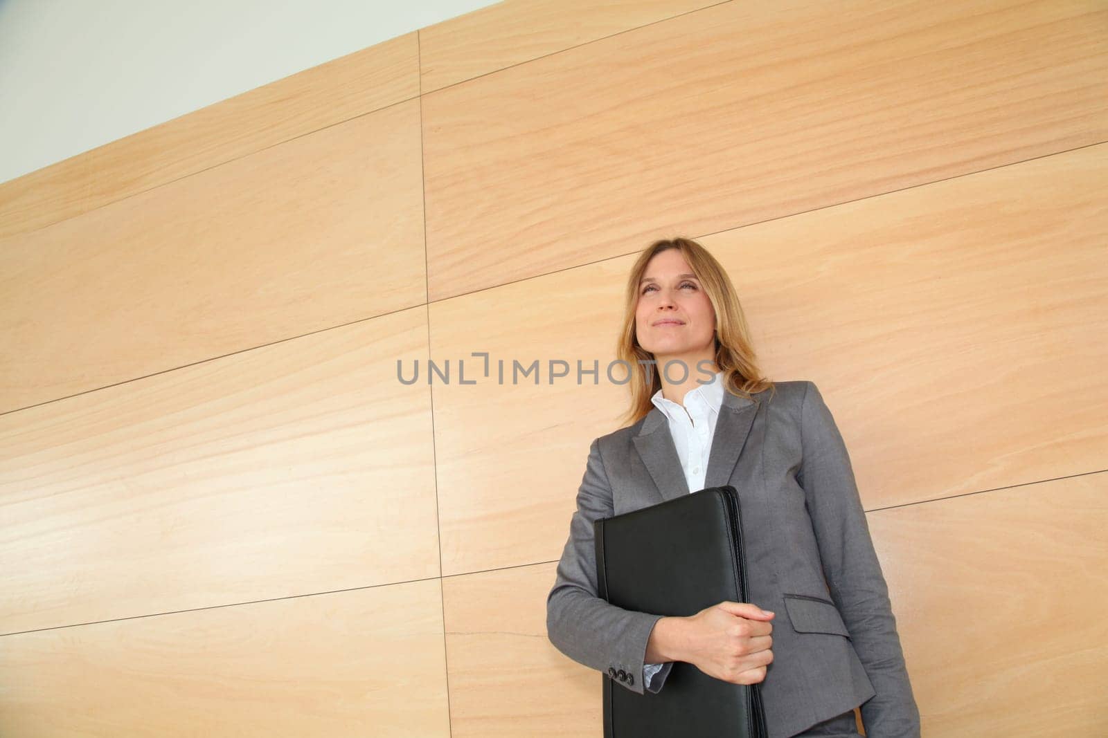 Businesswoman standing in hall against wall