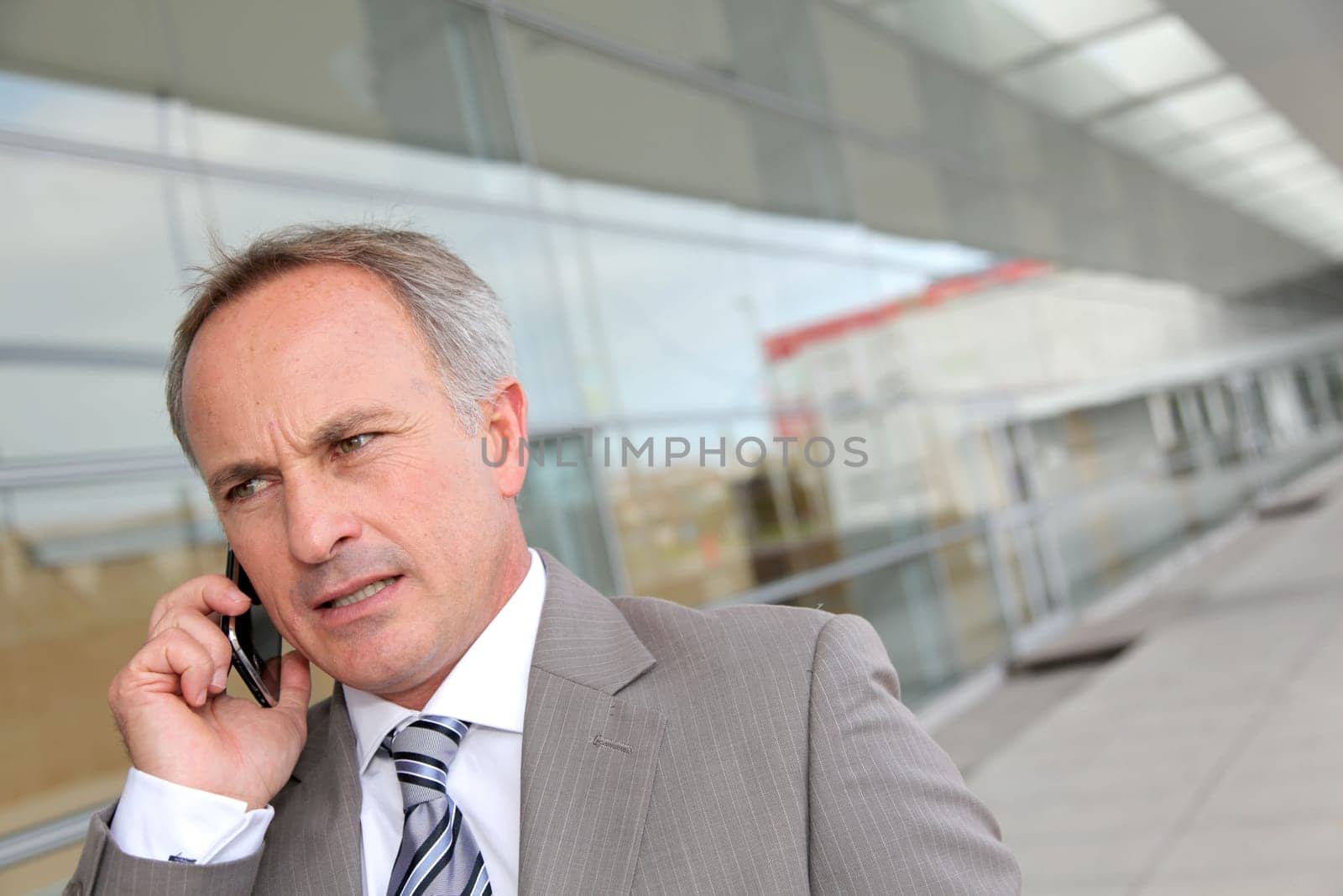 Businessman with mobile phone in front of modern building