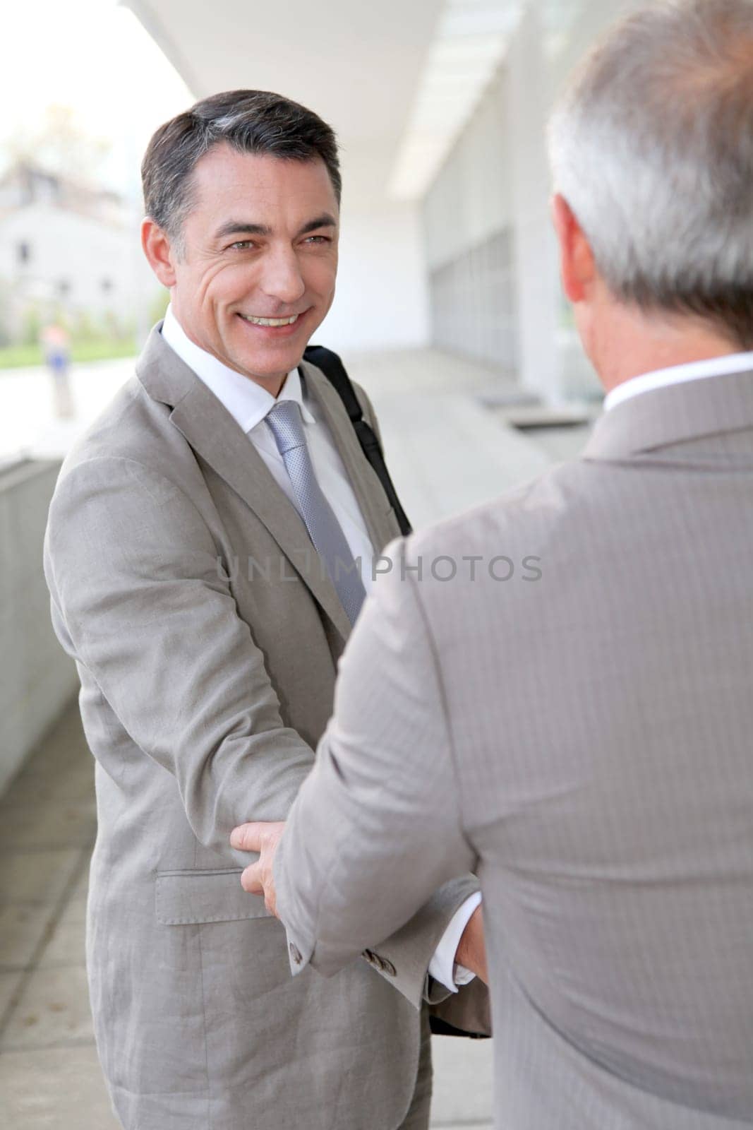 Businessmen shaking hands outside building