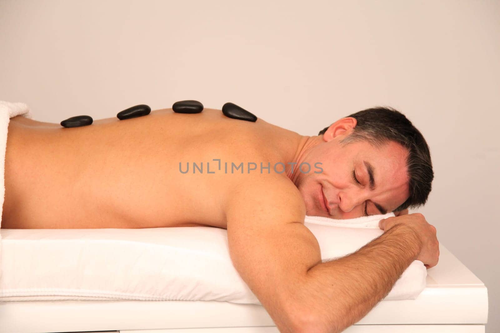 Man laying on massage bed with hot stones on his back
