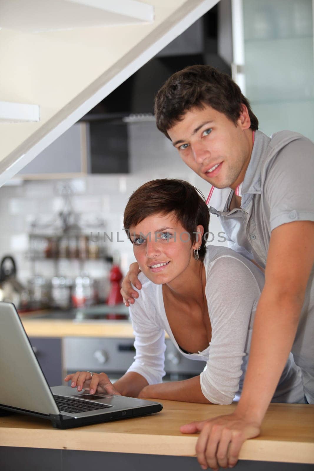Young couple standing in kitchen with laptop
